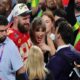 Travis Kelce couldn't help but smile at a Taylor Swift cardboard cutout at New Heights live show